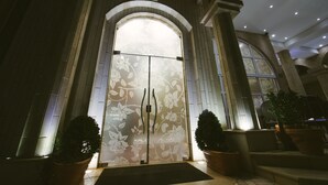 A grand entrance with a large arched doorway, flanked by columns and potted plants. - Hotel Flowers (Citluk)
