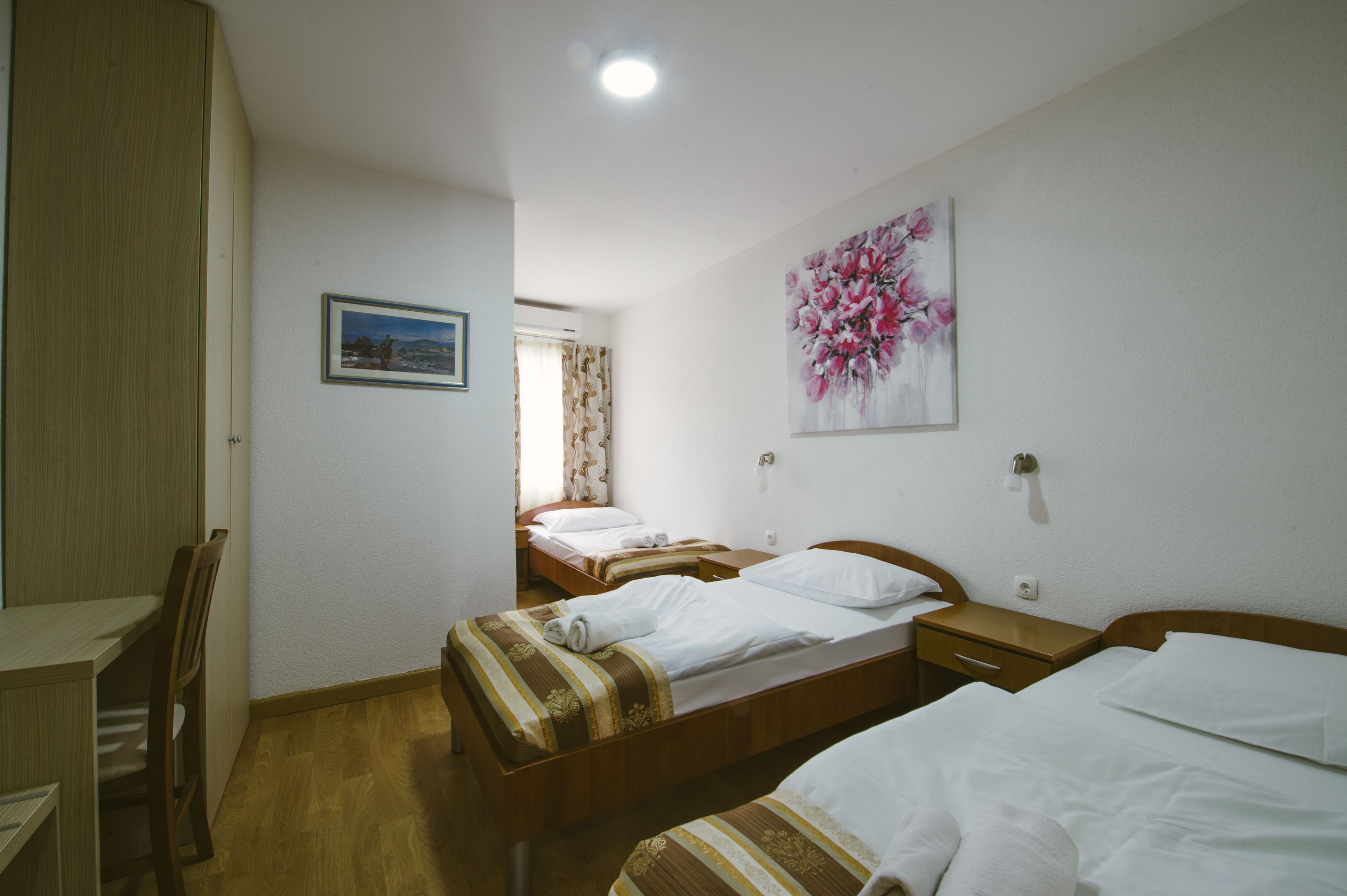 Een hotelkamer met twee enkele bedden, een houten bureau en een stoel.