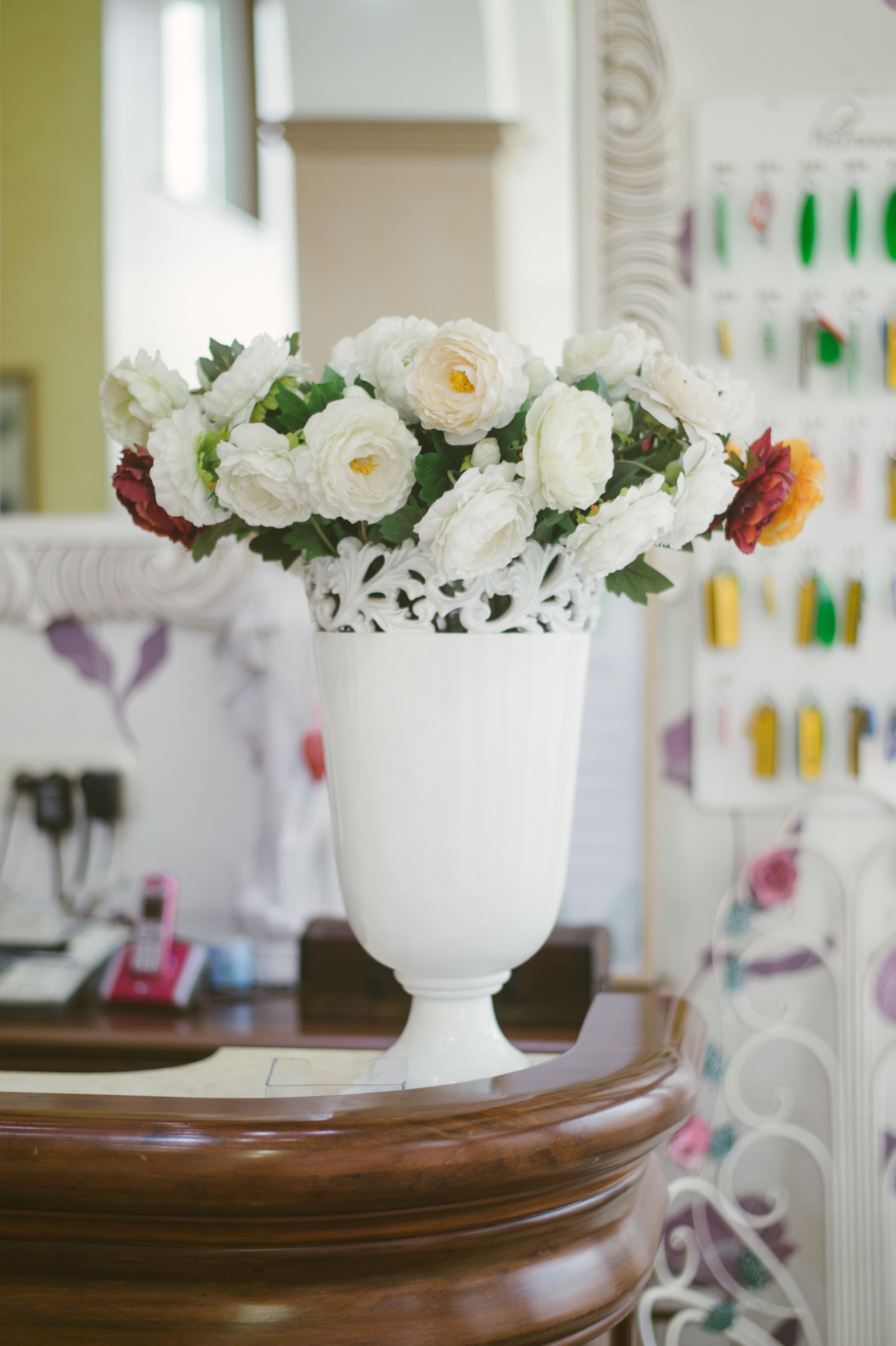 A white vase with flowers on a wooden table.