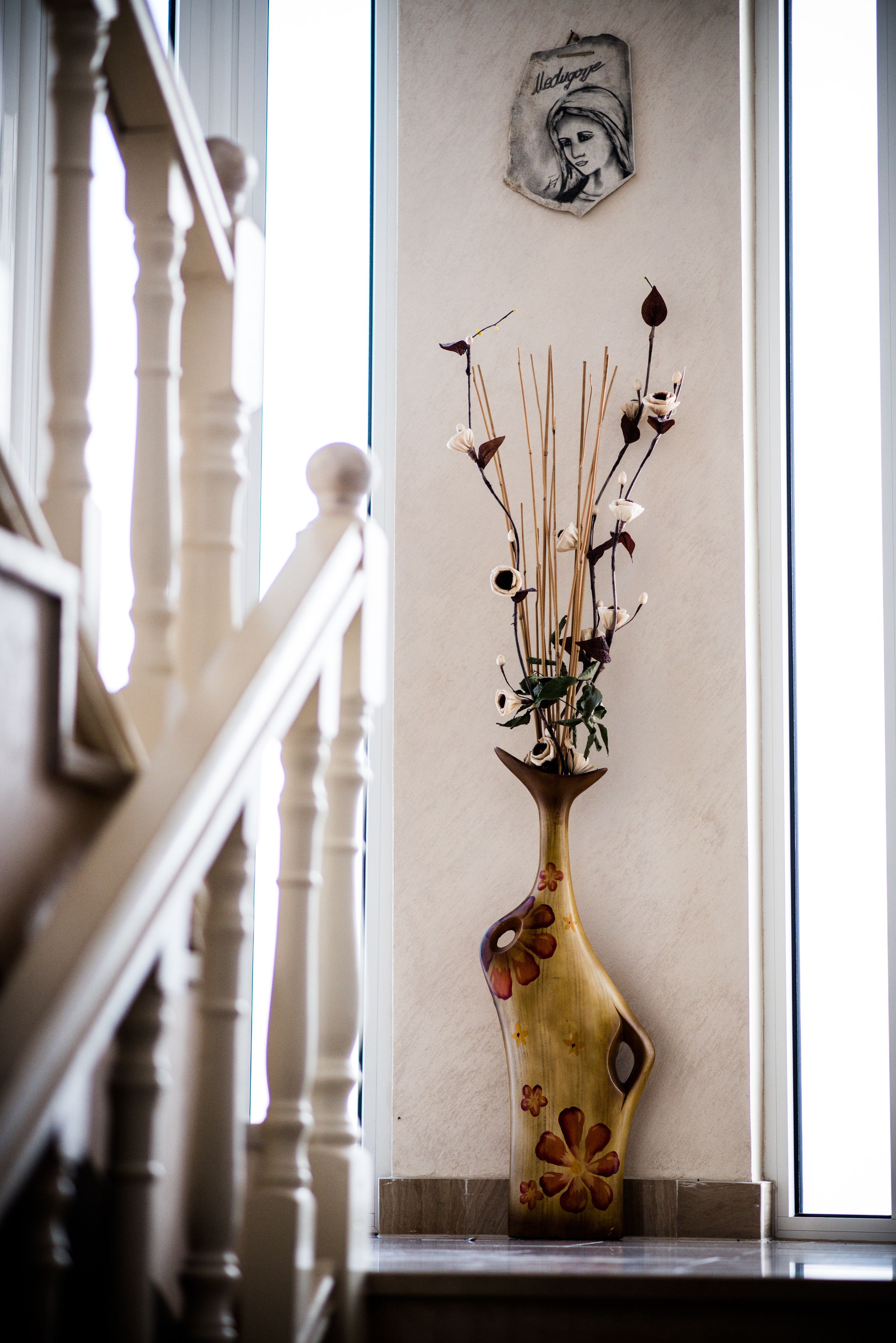 Un florero de madera con diseños florales sobre un alféizar.