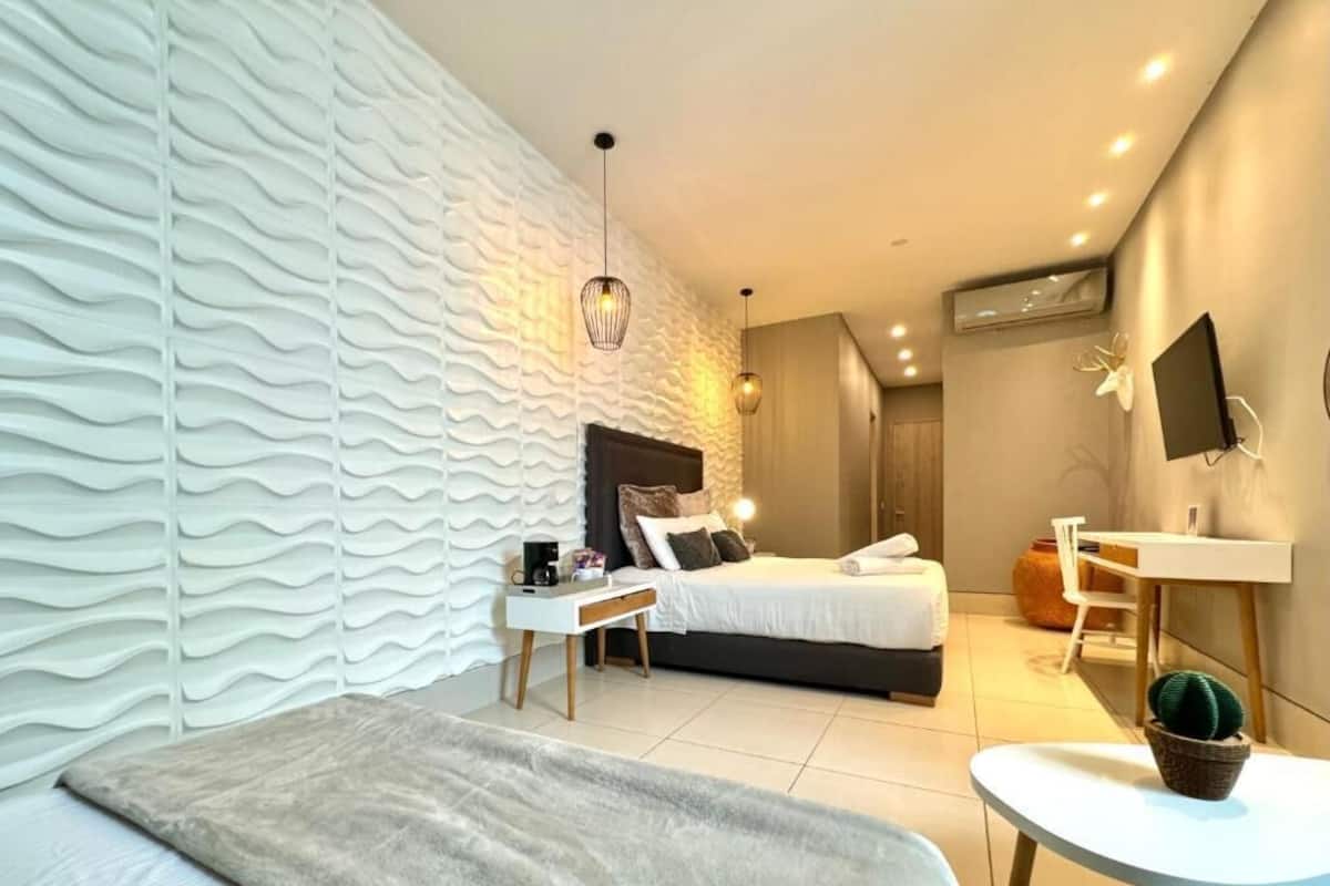 A modern bedroom with a bed, bedside table, and a desk with a chair.