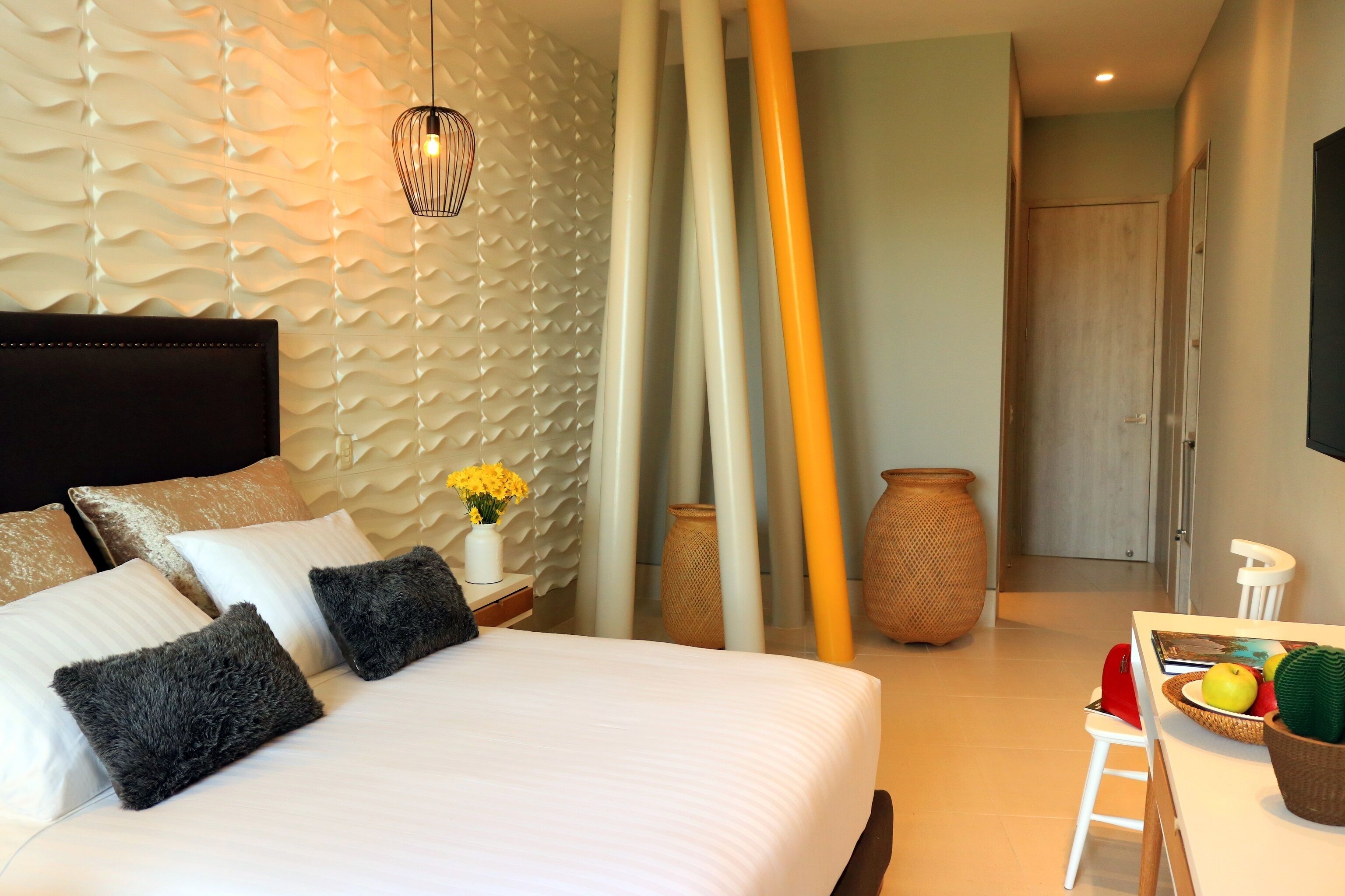 Ein modernes Hotelzimmer mit einem großen Bett, einem Nachttisch mit Blumenvase und einem Essbereich mit Tisch für zwei Personen.