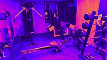 A gym with various exercise equipment, including a bench press, dumbbells, and a squat rack.