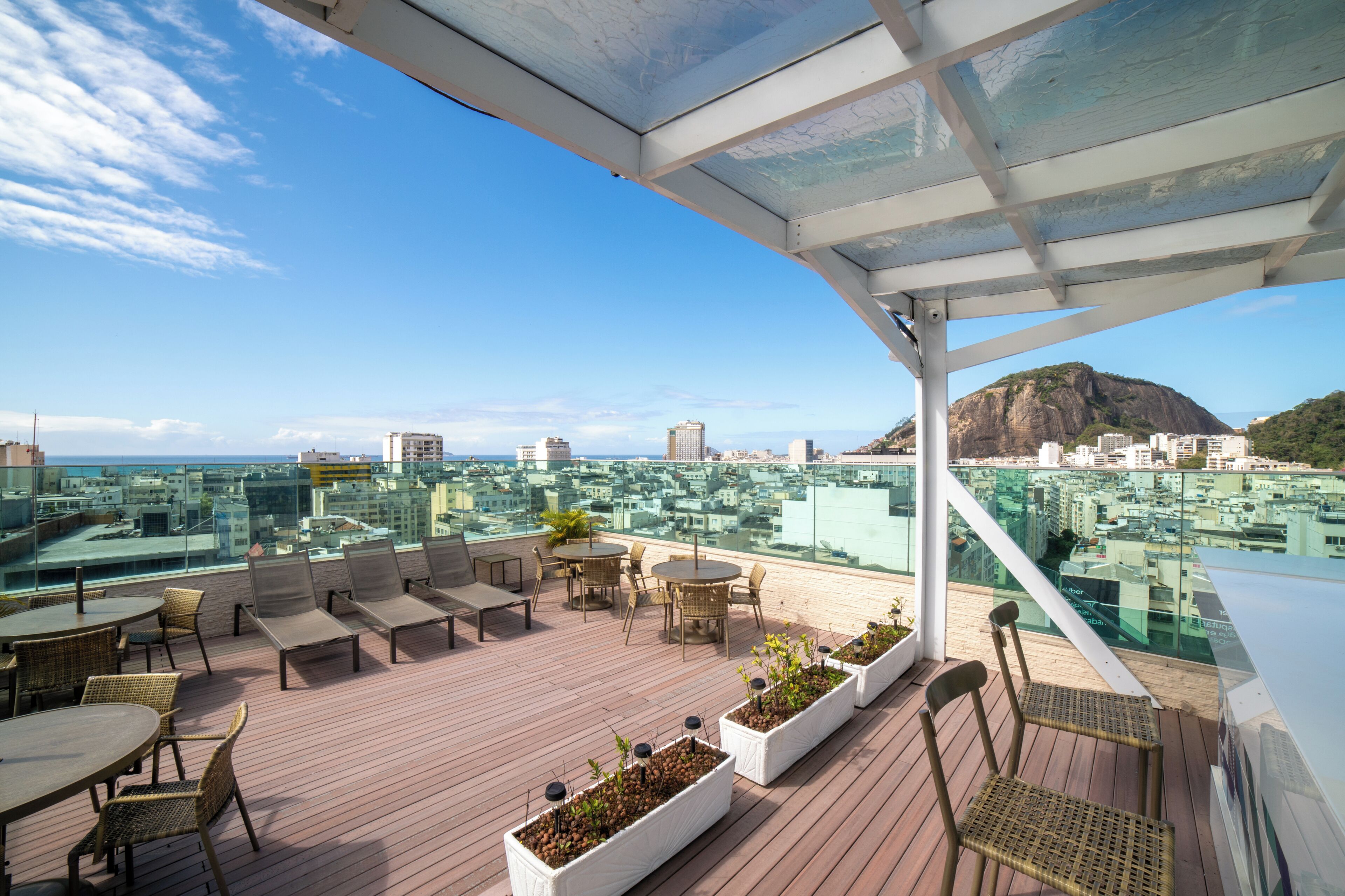 A rooftop terrace with outdoor seating, potted plants, and a city view.