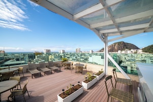 A rooftop terrace with outdoor seating, potted plants, and a city view.