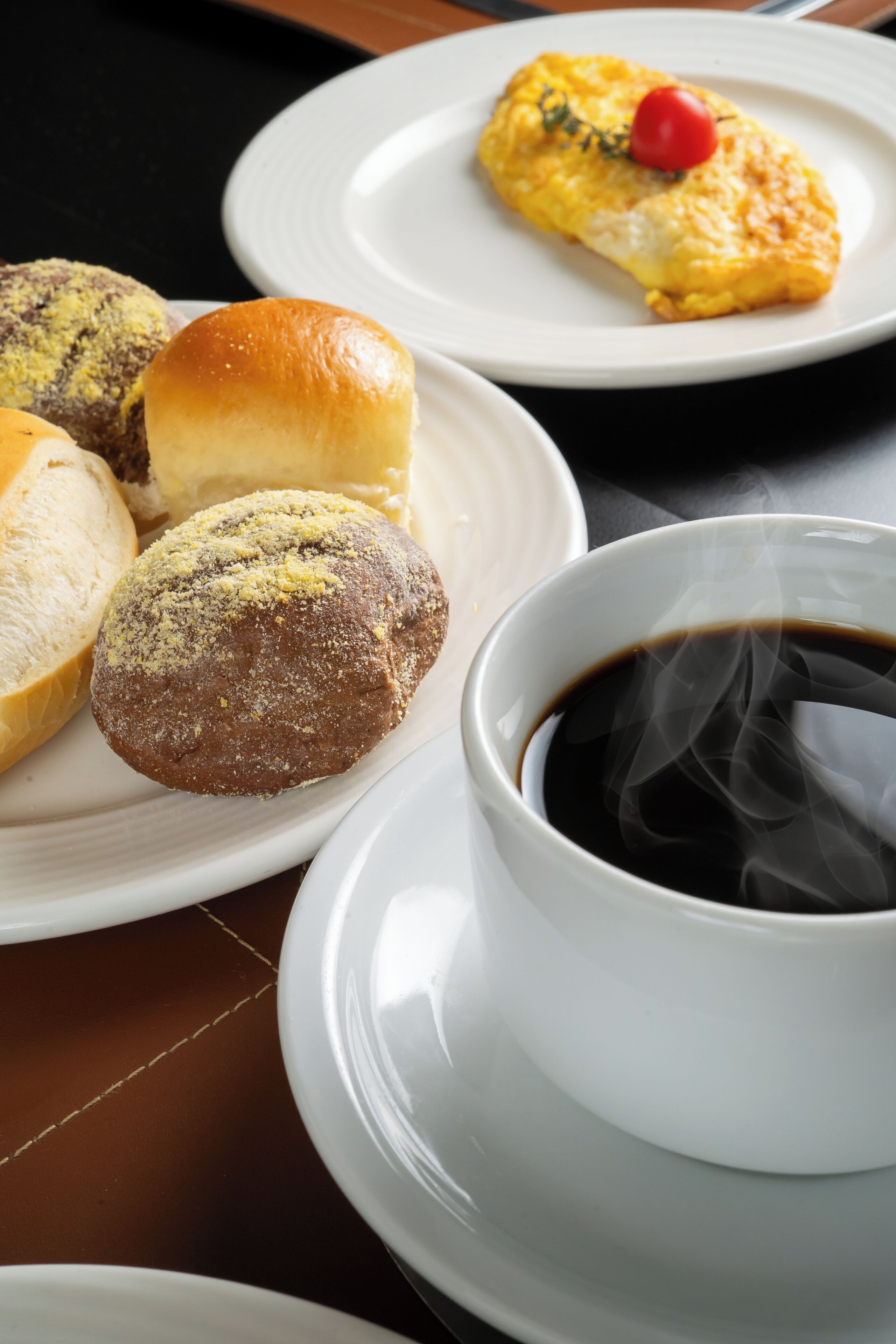A table with plates of pastries and a cup of coffee.
