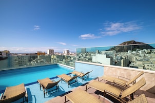 Une piscine sur le toit, dotée de chaises longues et offrant une vue sur la ville.