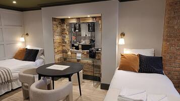 A hotel room with two beds, a small table, and a seating area.