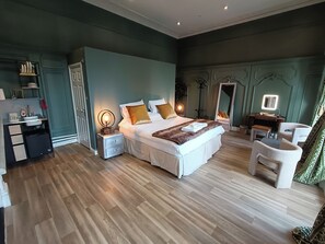A bedroom with a large bed, bedside tables, a desk, and a chair. - Rooms on The Prom (Cheltenham)