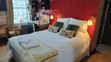 A neatly made bed with a white and green patterned bedspread, two decorative pillows, and two wall-mounted reading lamps.