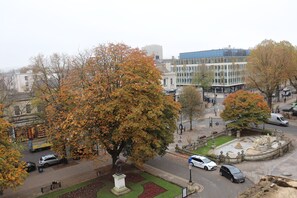 A park with a statue, a fountain, and a building in the background. - Rooms on The Prom (Cheltenham)