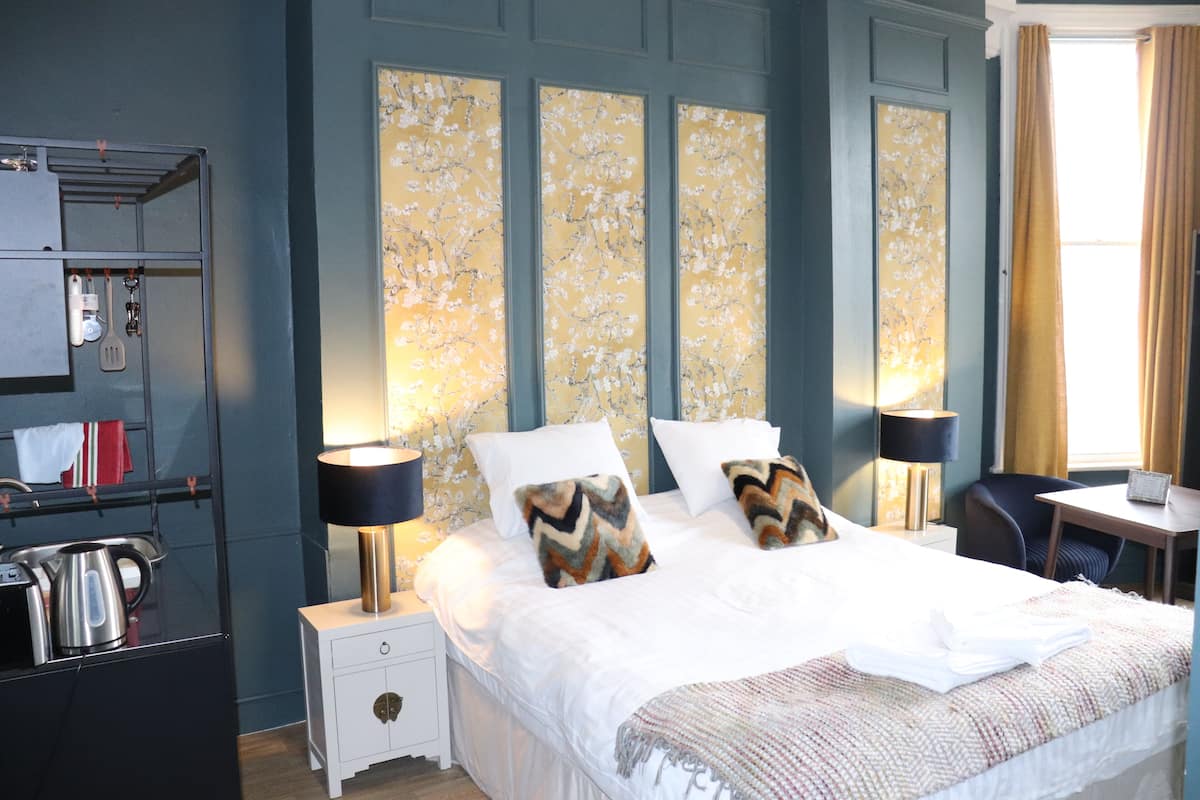 A hotel room with a large bed, two bedside tables, a desk, and a wardrobe.