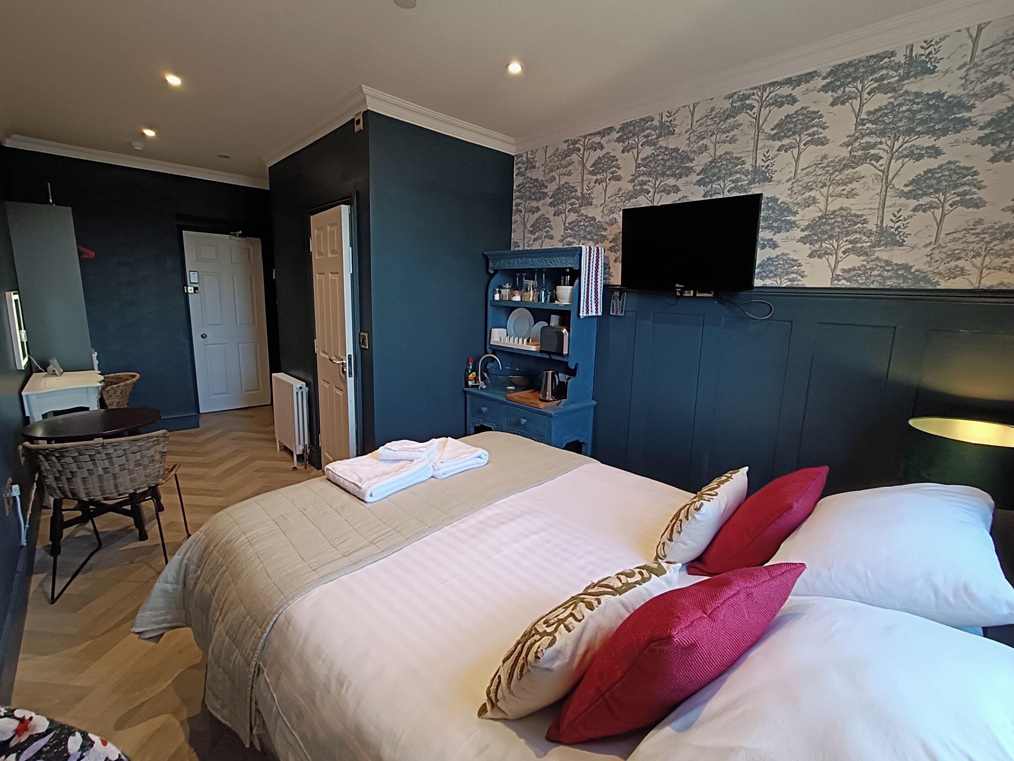 A hotel room with a bed, a desk, a chair, a TV, and a bathroom.