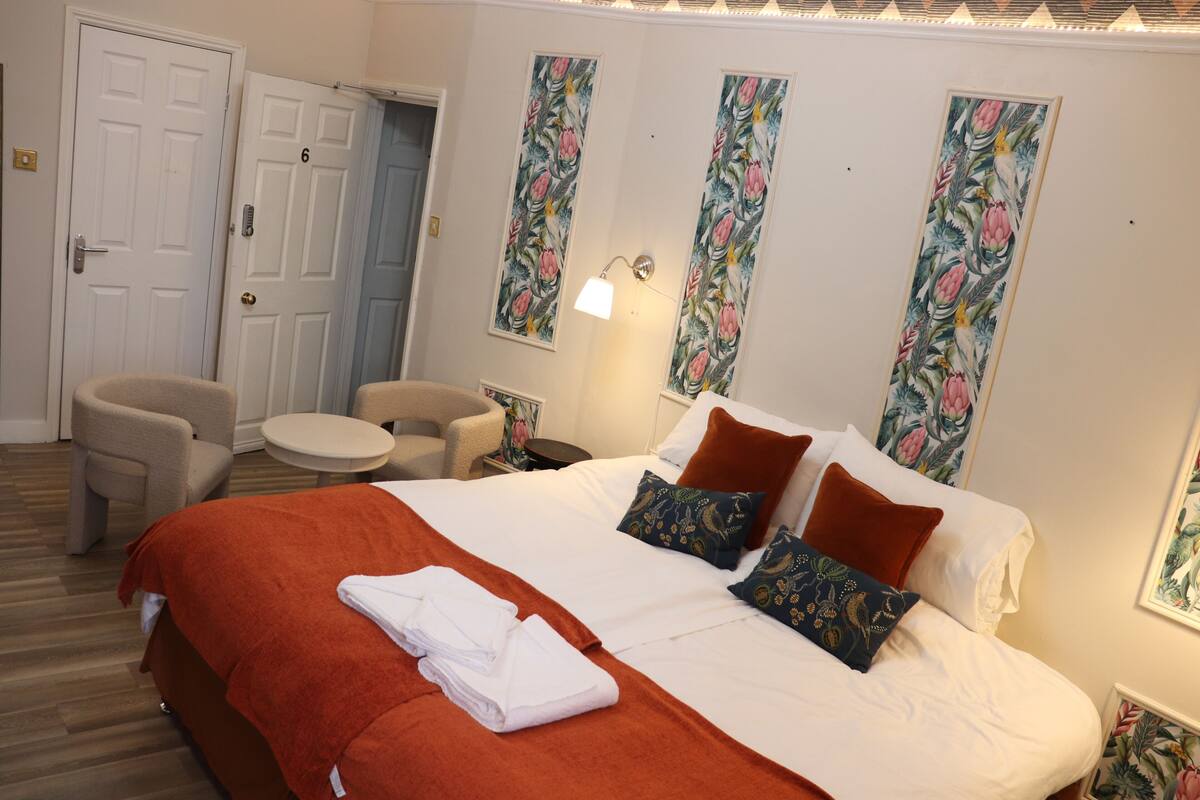 A hotel room with a bed, two chairs, a small round table, and a door.