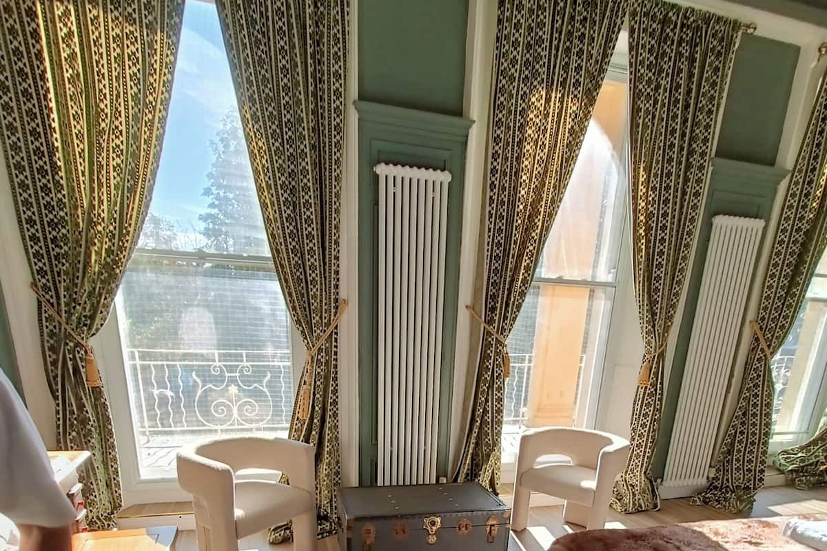 A room with a bed, two chairs, a small table, and a suitcase.
