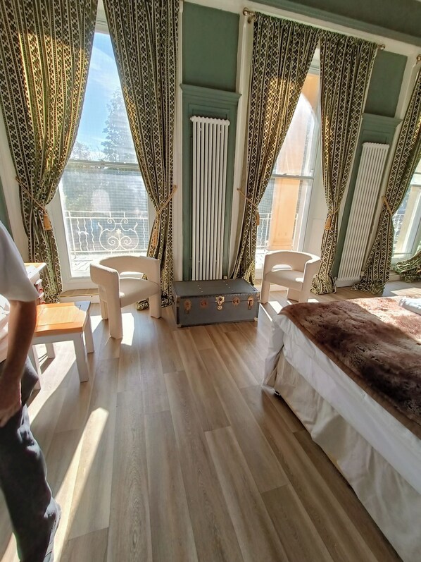 A room with a bed, two chairs, a small table, and a suitcase. - Rooms on The Prom (Cheltenham)