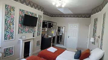 A hotel room with two beds, a flat-screen TV, a fireplace, a mirror, and a door.