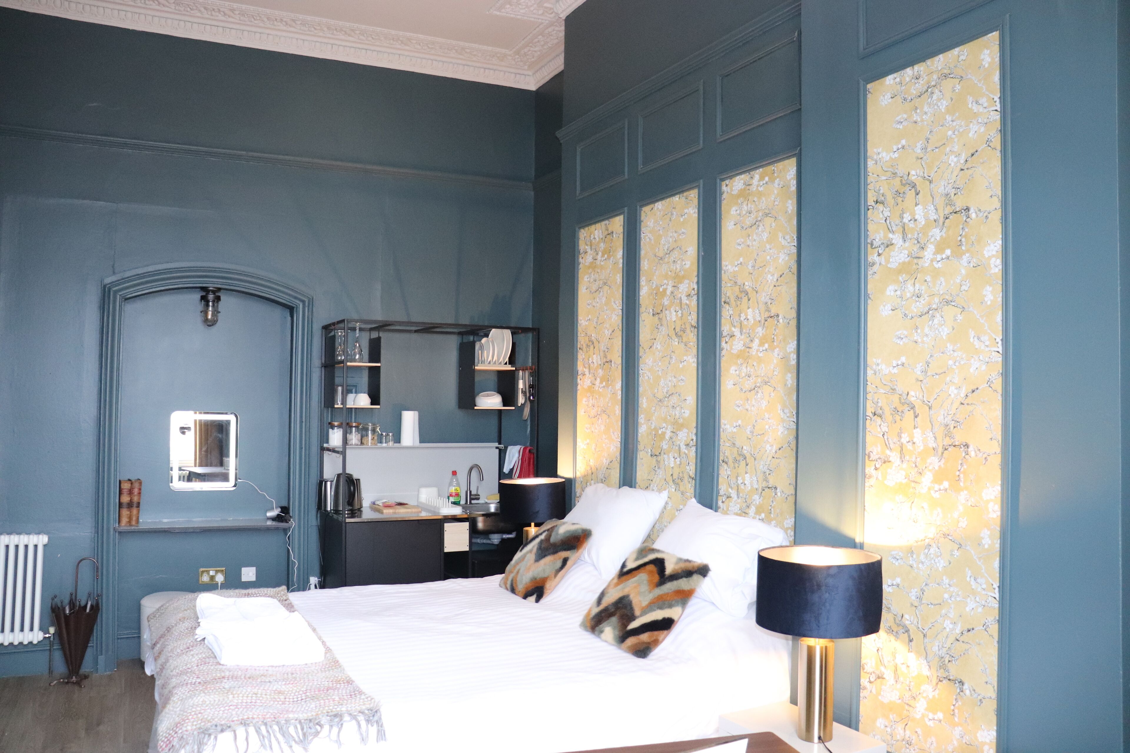 A bedroom with a bed, bedside table, lamp, and a wardrobe.