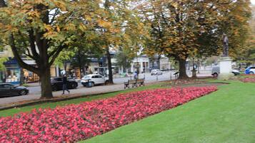 A park with a flower bed, benches, and a statue.