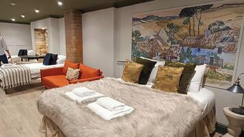 A modern bedroom with a large bed, a sofa, and a radiator.