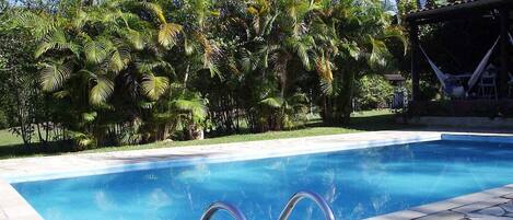 Una piscina al aire libre, sillones reclinables de piscina