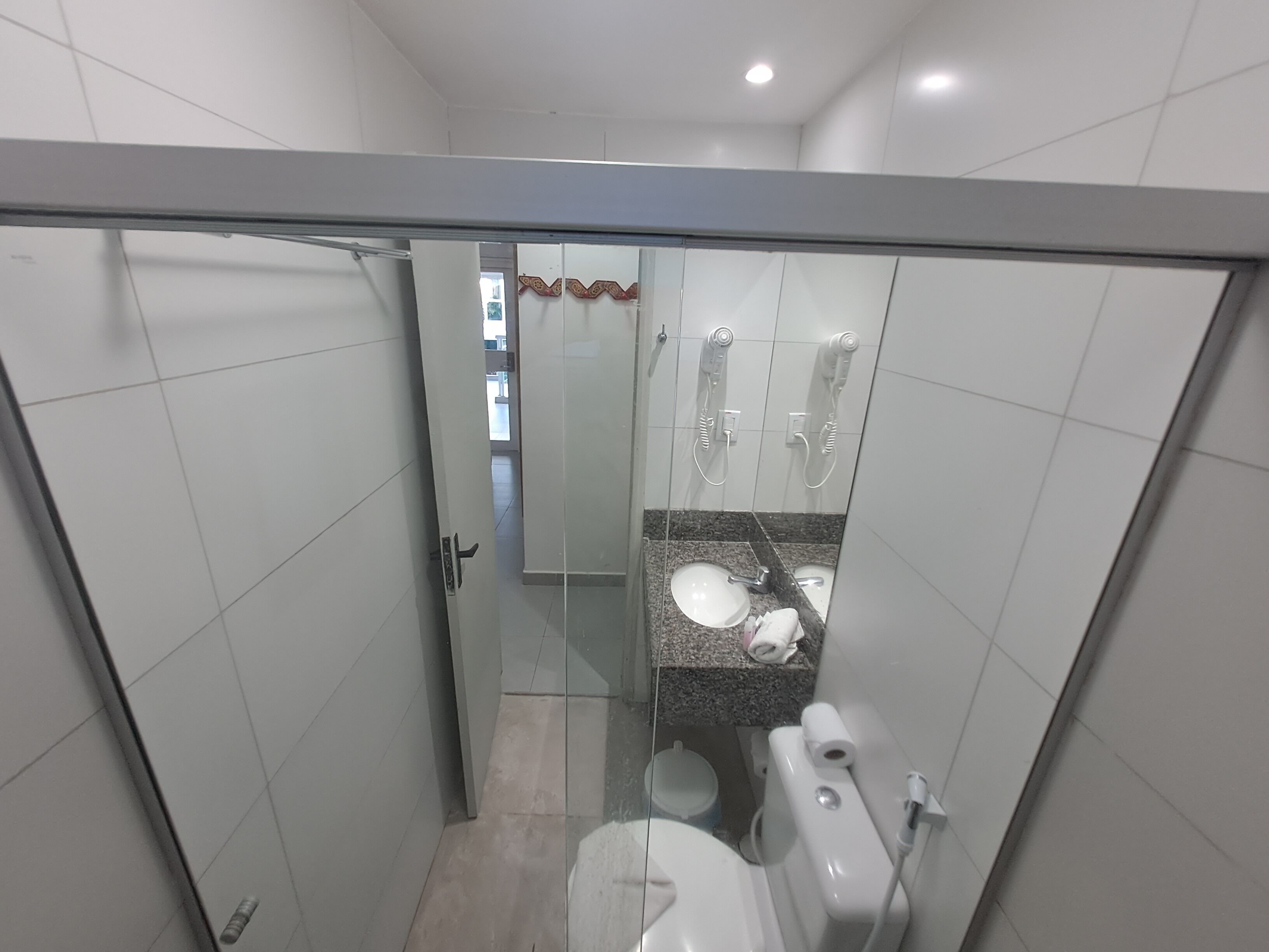 A modern bathroom with a glass shower enclosure, a toilet, and a sink with a granite countertop.