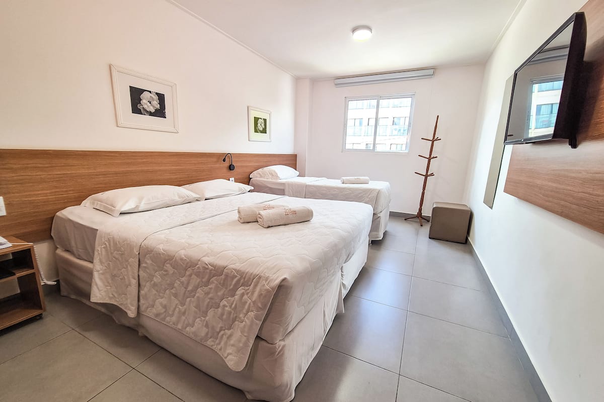 Habitación de hotel con dos camas, una mesita de noche, un espejo y una ventana.