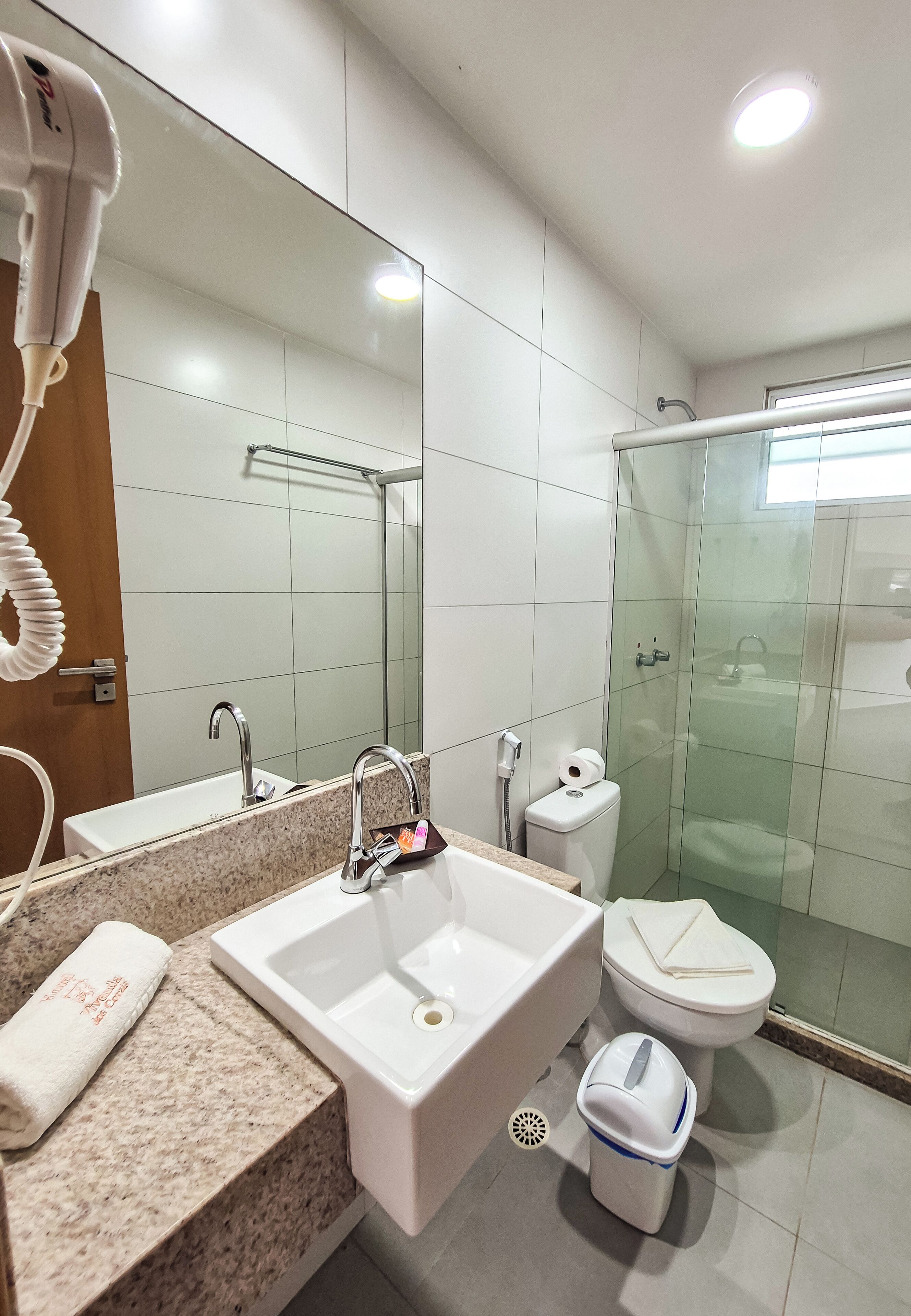 A modern bathroom with a large mirror, a sink, a toilet, and a shower area.