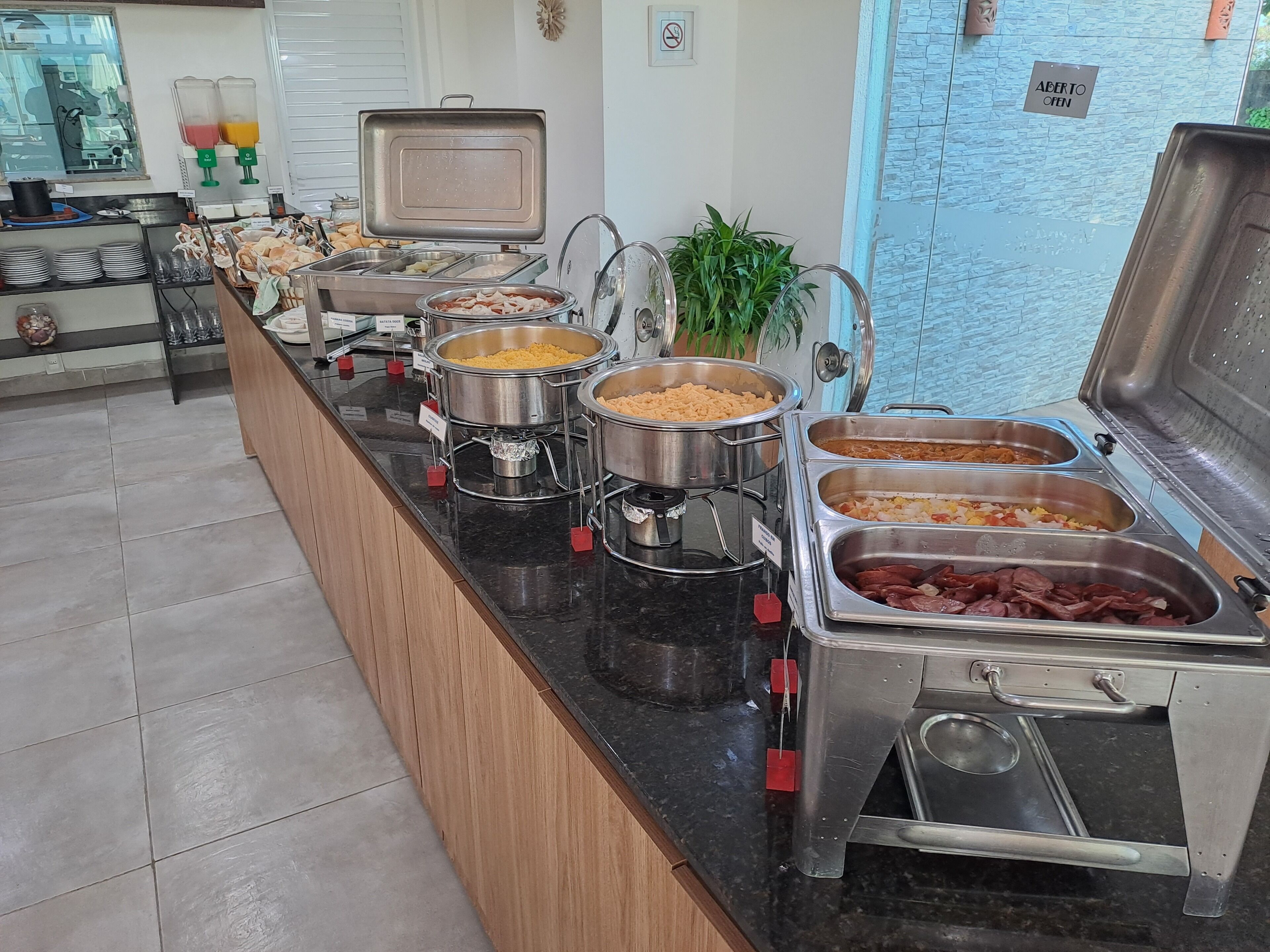 A buffet setup with various food items and a juice dispenser.