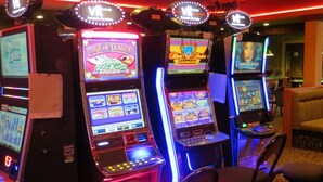 A row of slot machines in a dimly lit room with red neon lights. - Key West Inn (Devon)