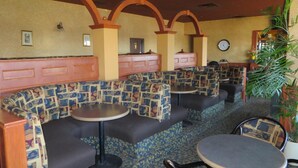 A restaurant with booth seating, small round tables, and a clock on the wall.