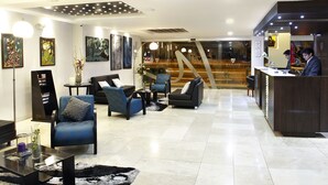 A modern hotel lobby with seating areas, a reception desk, and artwork on the walls. - Hotel Valgus (Cuenca)