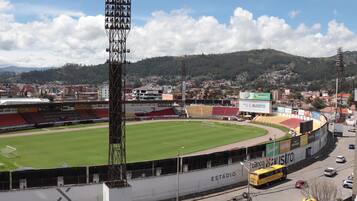 A stadium with a green field, seating areas, and a tall light tower.