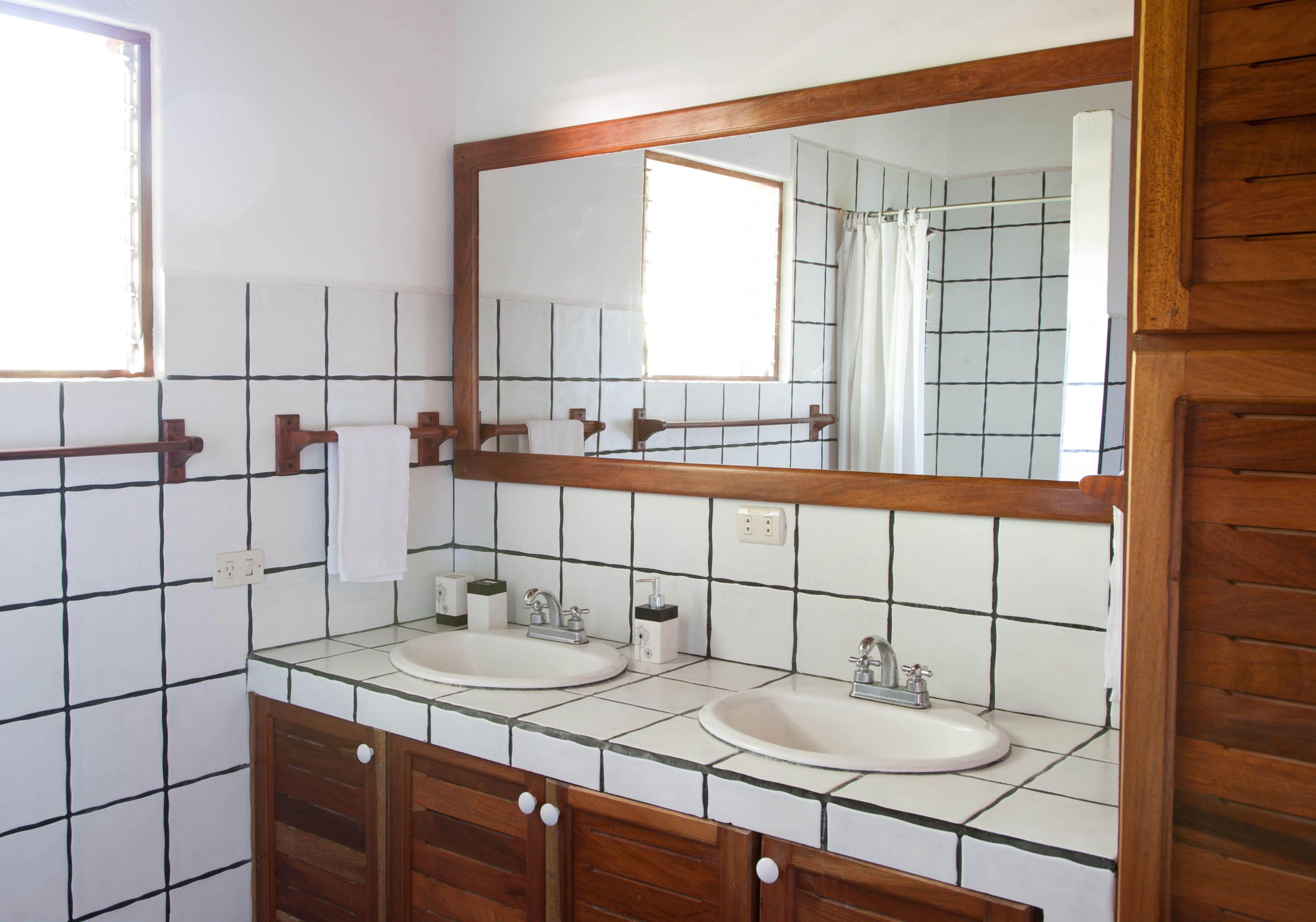 Une salle de bain avec deux lavabos, un grand miroir et des meubles en bois.