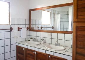 A bathroom with two sinks, a large mirror, and wooden cabinets.