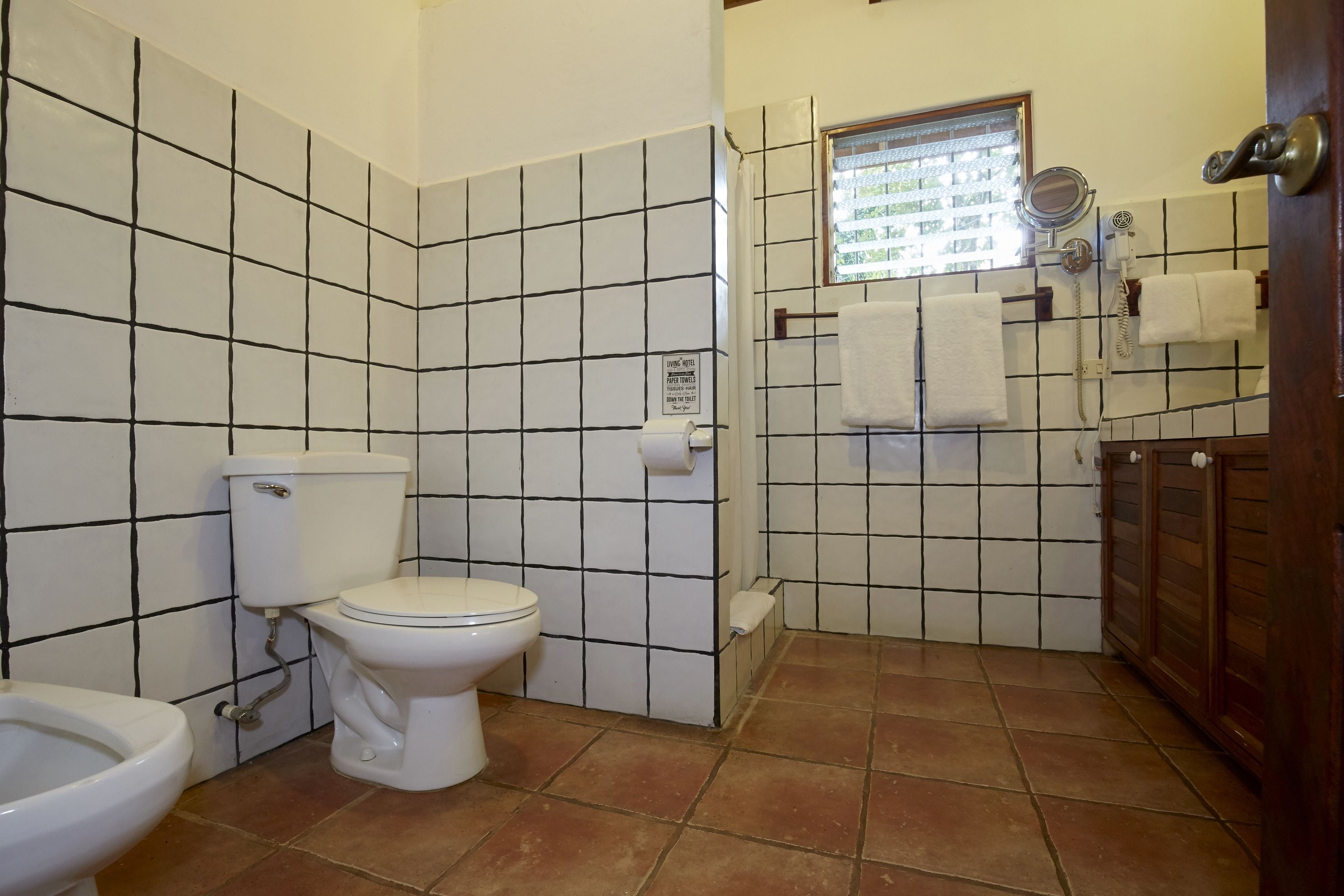 A bathroom with a toilet, bidet, and tiled walls.