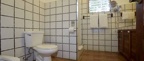 A bathroom with a toilet, bidet, and tiled walls.
