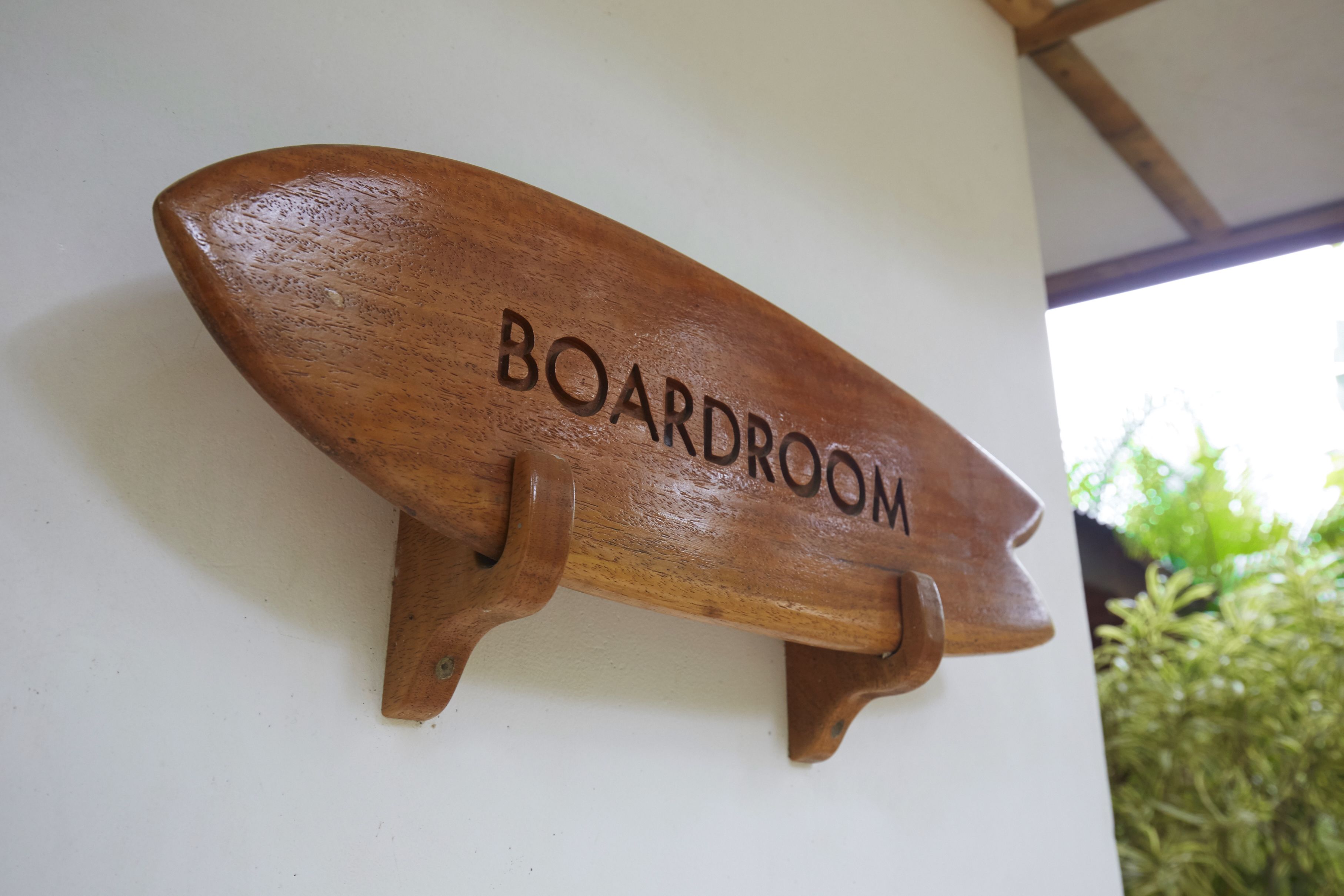Una placa de madera con la palabra 'BOARDROOM' colocada en una pared.