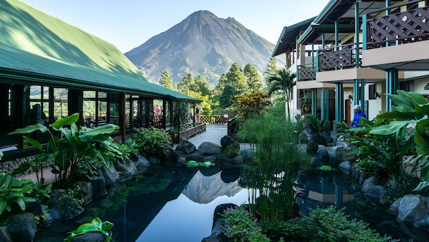 A hotel with a mountain view, a reflective pond, and lush greenery. - Arenal Observatory Lodge & Trails (La Fortuna)