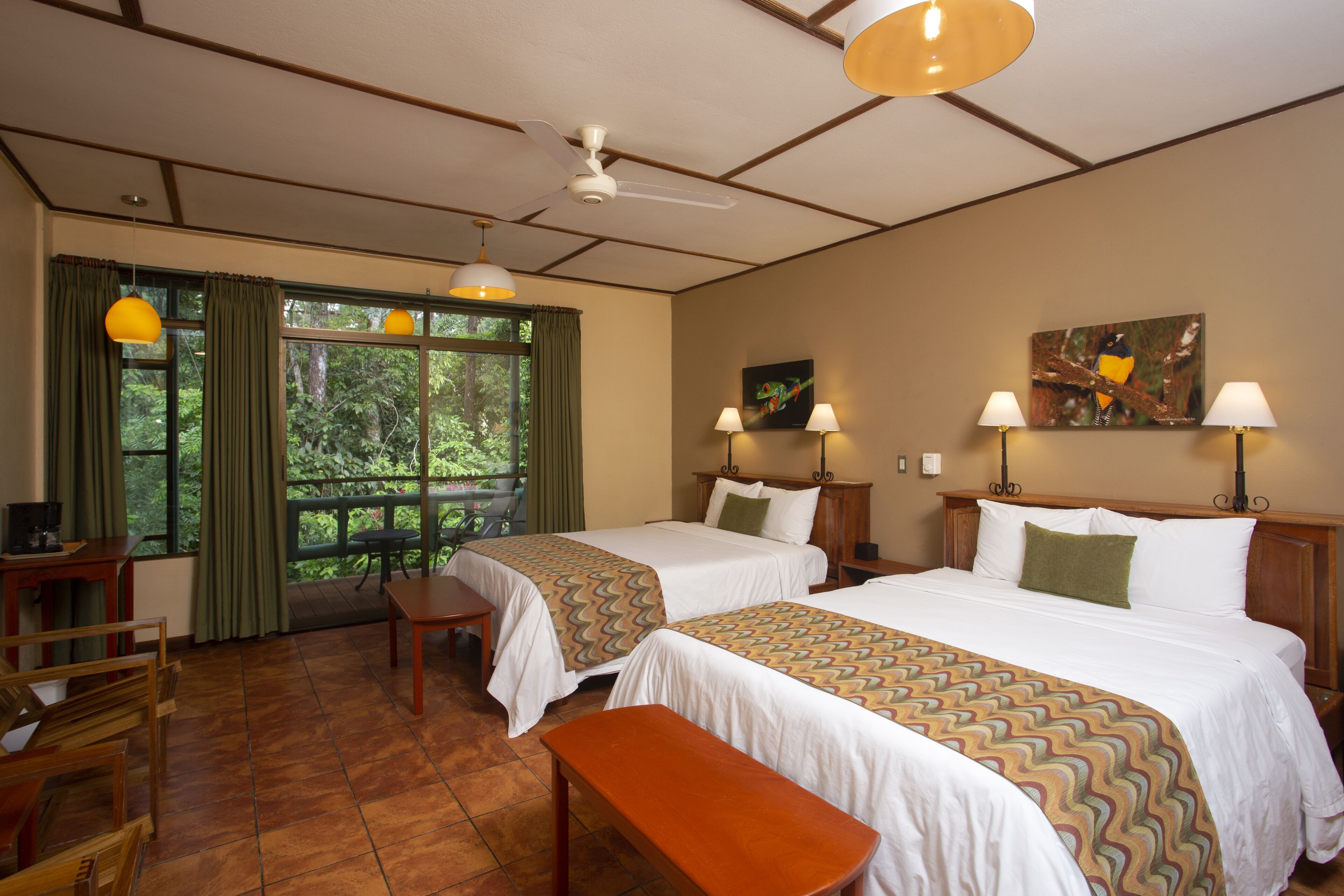 A hotel room with two beds, a desk, a chair, and a view of the outdoors.