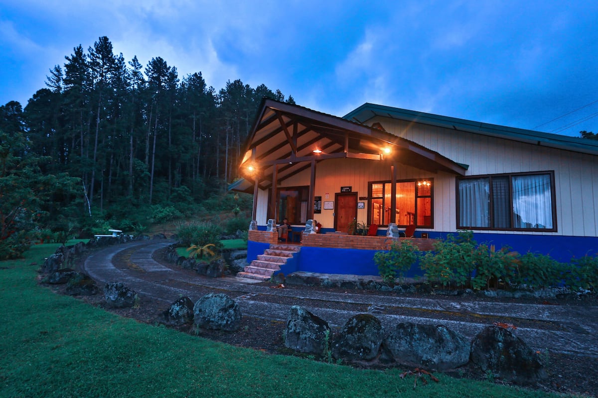 A lodge with a covered porch, a wooden deck, and a stone pathway leading to the entrance.