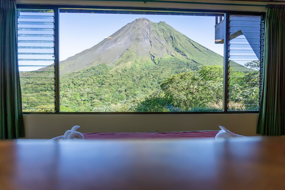 A room with a large window offering a view of a mountain.