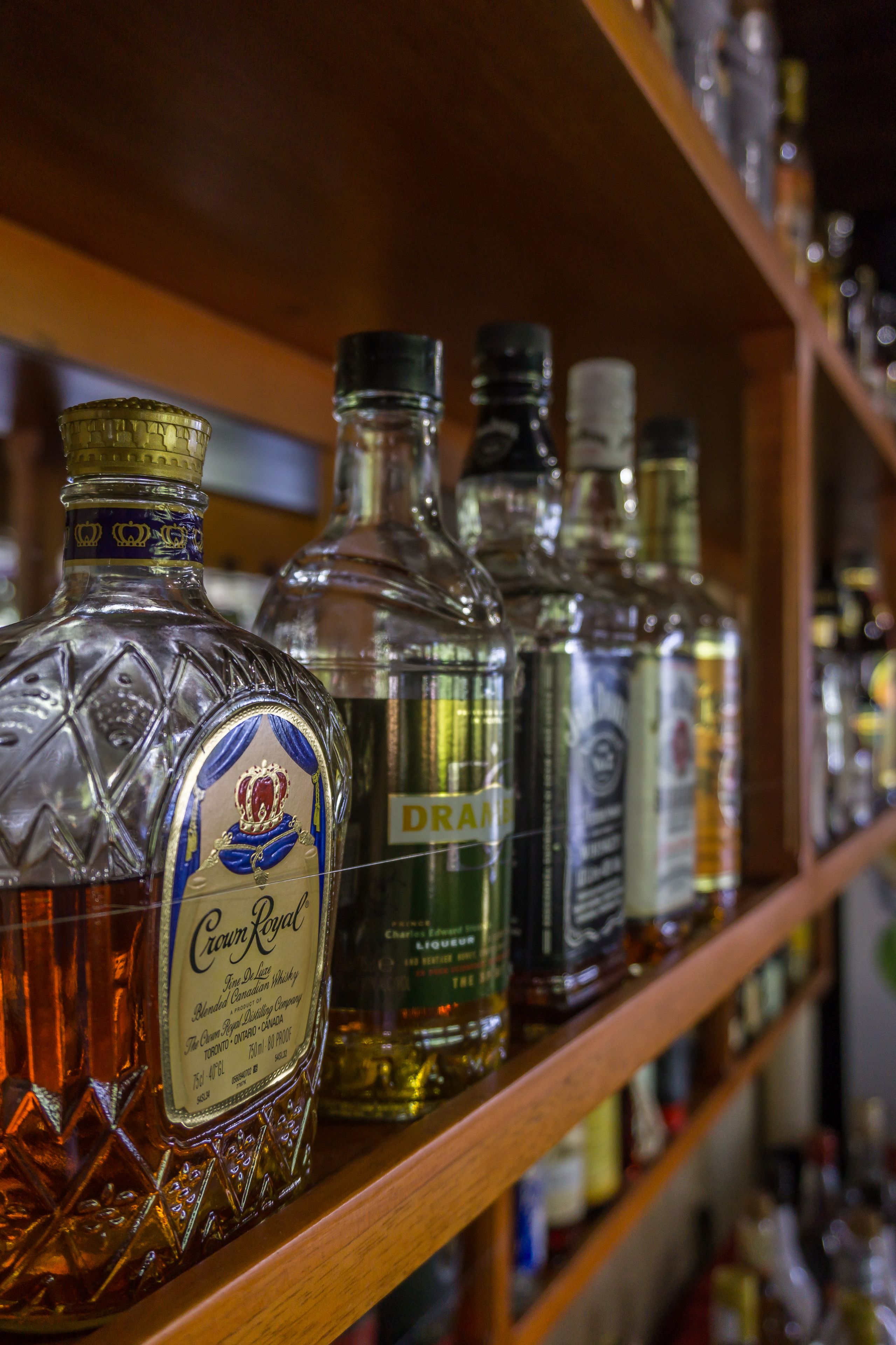 A shelf with various liquor bottles, including Crown Royal and Drambuie.