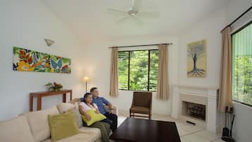 Una sala de estar con un sofá, una mesa de centro, una chimenea y un ventanal con cortinas.
