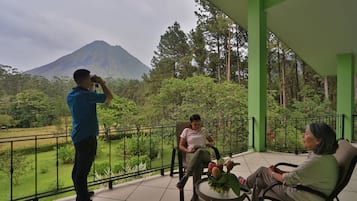 Un balcón con vistas a la montaña, una mesa con flores y dos personas sentadas.
