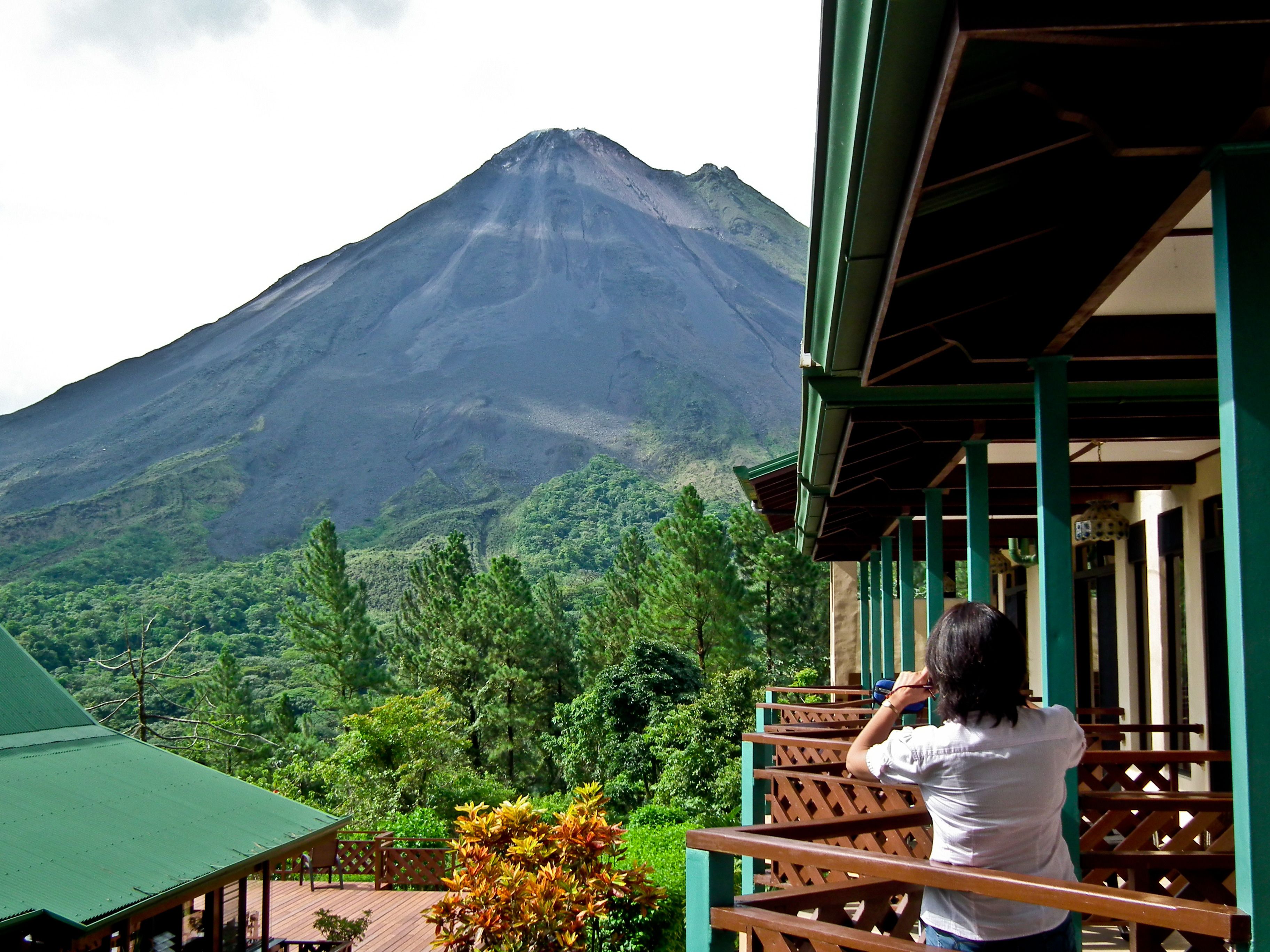 A view of a mountain from a wooden balcony with a green roof.