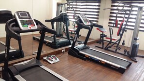 Un gimnasio con cintas de correr, bicicletas estáticas y máquinas de pesas.