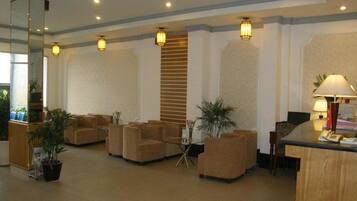 A lobby with a reception desk, several sofas, and potted plants.