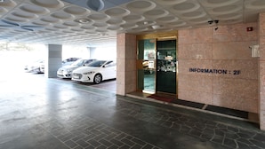 A parking garage entrance with a modern ceiling design, a sign reading "INFORMATION: 2F", and several parked cars. - SB Guest House (Suwon)
