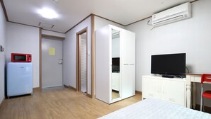 A hotel room with a bed, a TV, a wardrobe, a microwave, and an air conditioner. - SB Guest House (Suwon)